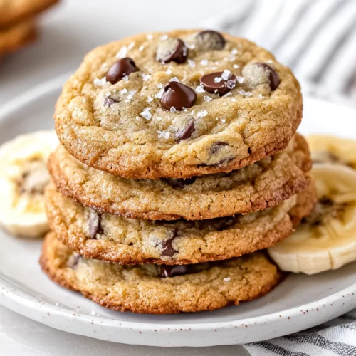 Soft And Irresistible Banana Chocolate Chip Cookies Recipe 3 Stack Of Banana Chocolate Chip Cookies On A White Plate, Garnished With Banana Slices And Flaky Sea Salt