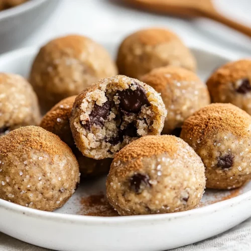 No-Bake Banana Protein Balls: Easy, Healthy Snacks For Anytime 3 Cinnamon-Coated Banana Protein Balls On A White Plate With Chocolate Chips And A Wooden Spoon Of Cinnamon Sugar Nearby