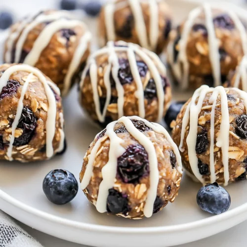 Blueberry Energy Balls: A Healthy, No-Bake Treat 3 Blueberry Energy Balls On A White Plate, Drizzled With Melted White Chocolate And Topped With Chopped Blueberries.