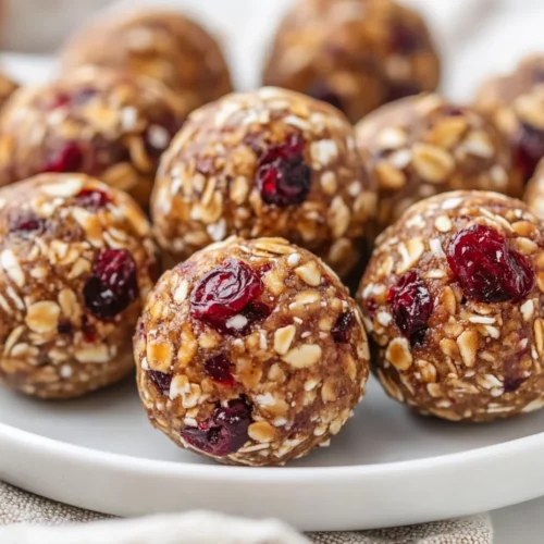 Cranberry Almond Energy Balls: Quick, Healthy, And No-Bake 3 Cranberry Almond Energy Balls On A White Plate, Garnished With Crushed Almonds And Oatmeal Flecks.