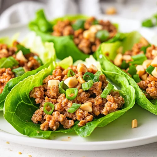 Ground Turkey Lettuce Wraps On A White Plate Garnished With Peanuts And Green Onions, Showcasing Fresh Ingredients.