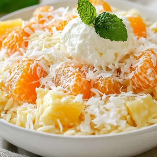 Holiday Ambrosia Salad Recipe – A Festive Family Favorite 3 Colorful Holiday Ambrosia Salad Served In A White Bowl, Topped With Whipped Topping And Garnished With Coconut.