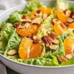 Mandarin Almond Salad With Romaine, Mandarin Oranges, And Sugared Almonds In A White Bowl, Drizzled With Vinaigrette
