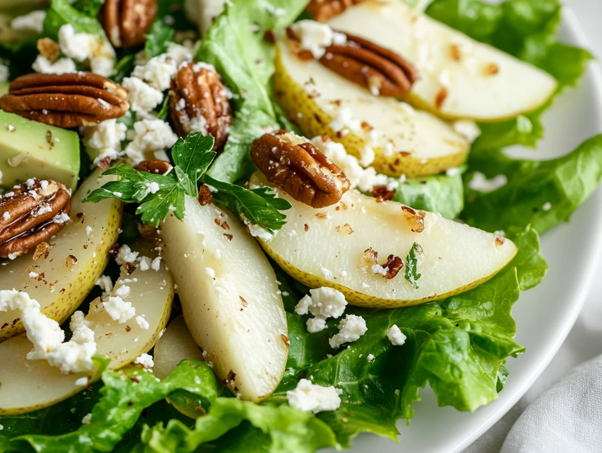 Roquefort Pear Salad Served On A White Plate, Topped With Candied Pecans And Fresh Parsley