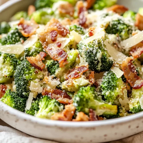 Warm Broccoli Caesar Salad With Bacon And Parmesan In A White Bowl, Topped With Crispy Panko And Drizzled With Dressing.