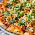 Buffalo Chicken Pizza With Guacamole On A White Plate Garnished With Cilantro And Green Onions