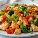 Colorful Gluten-Free Chicken Stir-Fry On A White Plate Topped With Green Onions And Bright Veggies