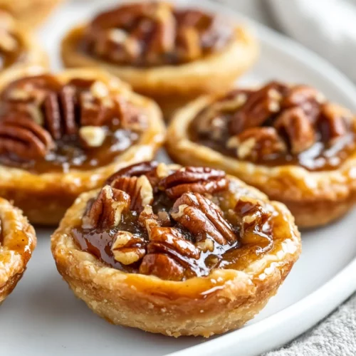 Plate Of Pecan Tassies With Golden Crust And Glossy Filling, Garnished With Toasted Pecans