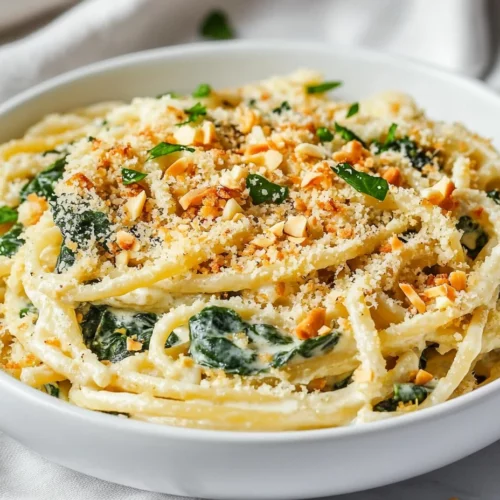 Creamy Spinach Artichoke Pasta In A White Bowl Topped With Crispy Panko And Almonds, Garnished With Parsley